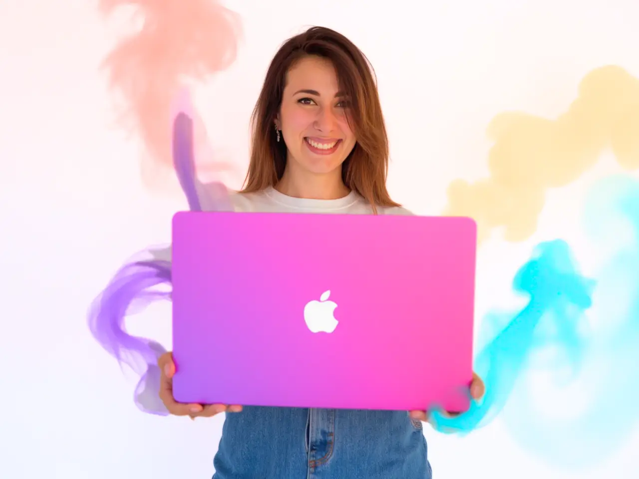 Laura G.Arias con MacBook rosa, diseño web en Daganzo con nubes coloridas de fondo