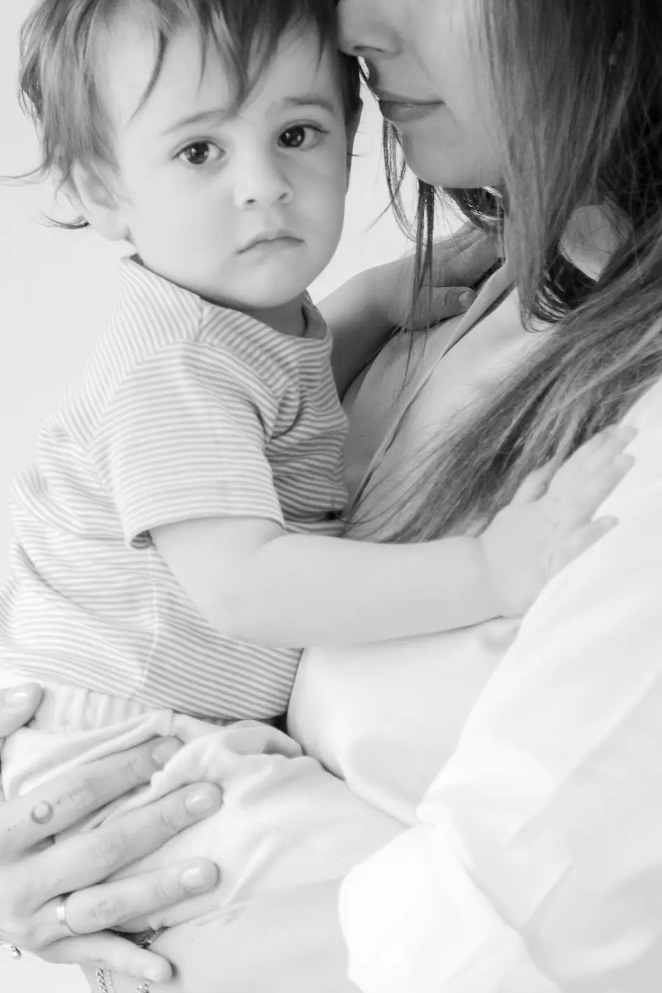 Fotografía en blanco y negro de un niño pequeño con el pelo corto sostenido cariñosamente por una mujer adulta, que apoya suavemente la barbilla en la cabeza del niño: un conmovedor reflejo de valores laborales y profundo respeto mutuo. Ambos tienen expresiones tranquilas. lauragarias
