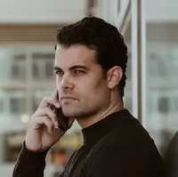 Hombre de pelo corto junto a ventana, hablando por teléfono y mirando a lo lejos. Javier Laín